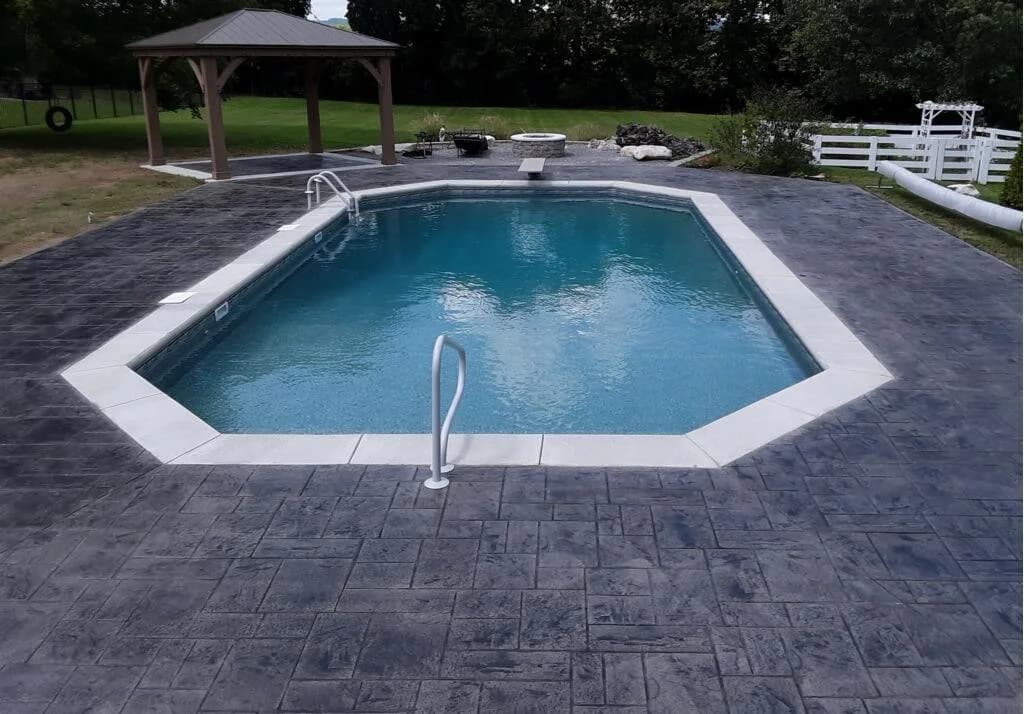 Pool with gazebo and dark stamped concrete deck