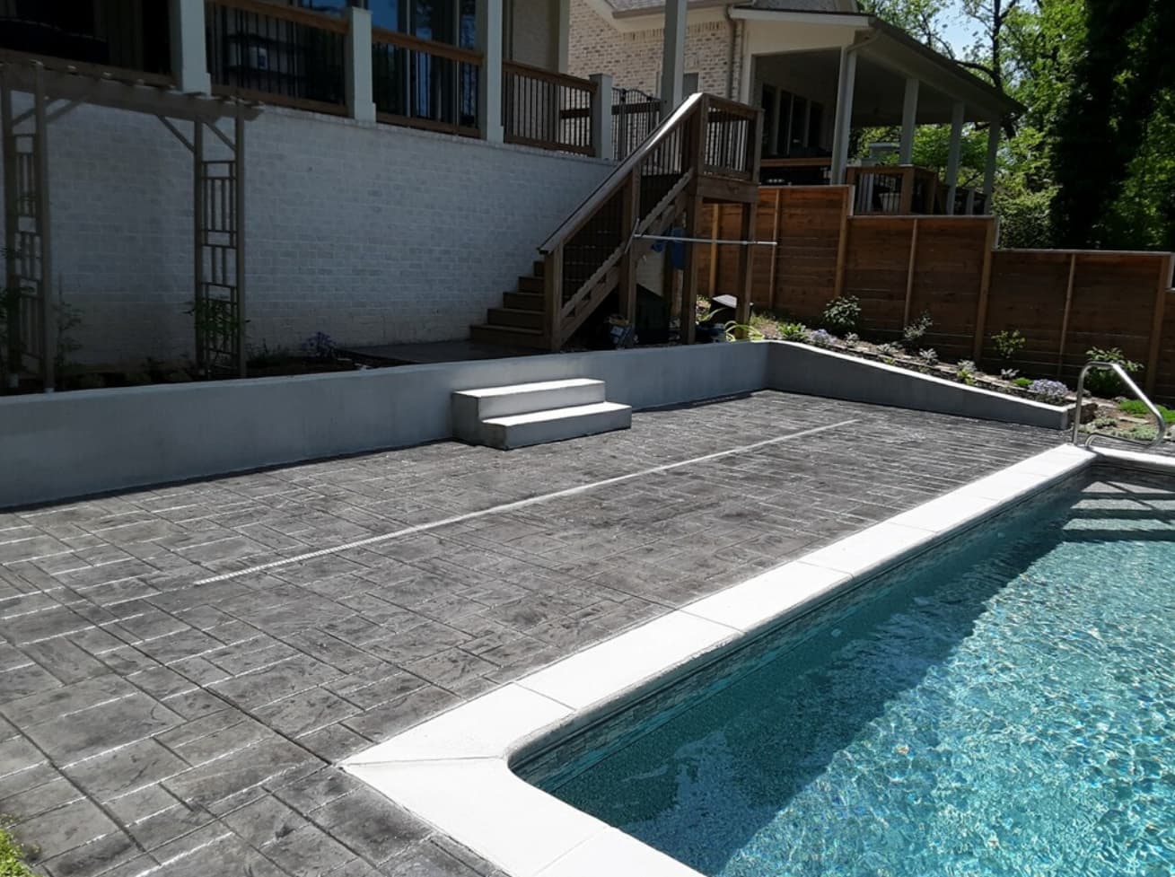 Vinyl pool with stamped concrete deck and retaining wall