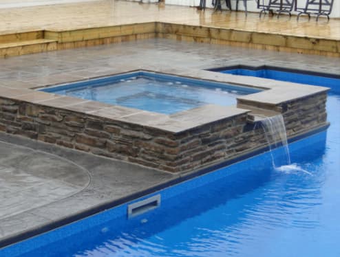 Stone spa with spillover into the pool