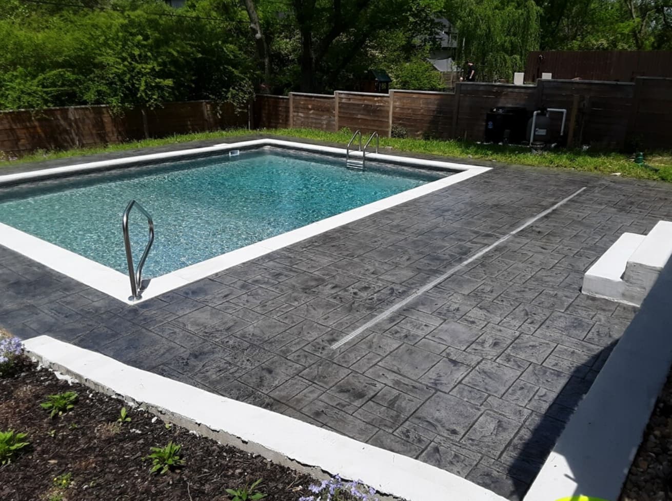 Vinyl pool with dark stamped concrete deck